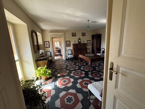 Ein Zimmer mit einem Schachbrettmuster auf dem Boden, einem Esstisch, Stühlen, einem Schrank und einer Tür.