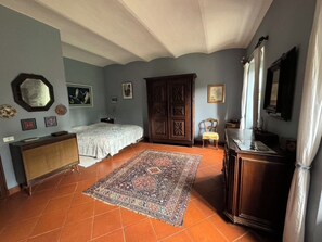 Ein Schlafzimmer mit einem Bett, einem Holzschrank, einem Heizkörper und einem großen Teppich.