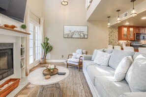 Ein Wohnzimmer mit Kamin, einer Couch, einem Couchtisch und einem Gemälde an der Wand.