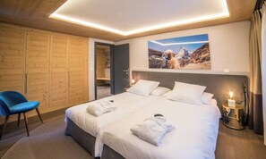 Ein Hotelzimmer mit einem großen Bett, einem blauen Sessel, einem Holzschrank und einem Bild an der Wand.