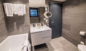 Ein modernes Badezimmer mit einer Badewanne, einem Waschbecken mit Spiegel und einer Toilette.