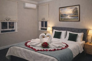 A hotel room with a bed, two bedside lamps, a painting on the wall, and a window with a decorative valance. - Charming Double Room with AC in Vibrant Istanbul (istanbul)