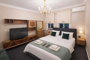 Una habitación de hotel con cama, televisión, mueble de almacenamiento de madera y una araña.