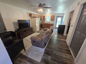 A living room with a sofa, a television, and a ceiling fan. - Cozy 1-bedroom apartment in enchanting Sparta surounded by trees and wilderness. (Sparta)