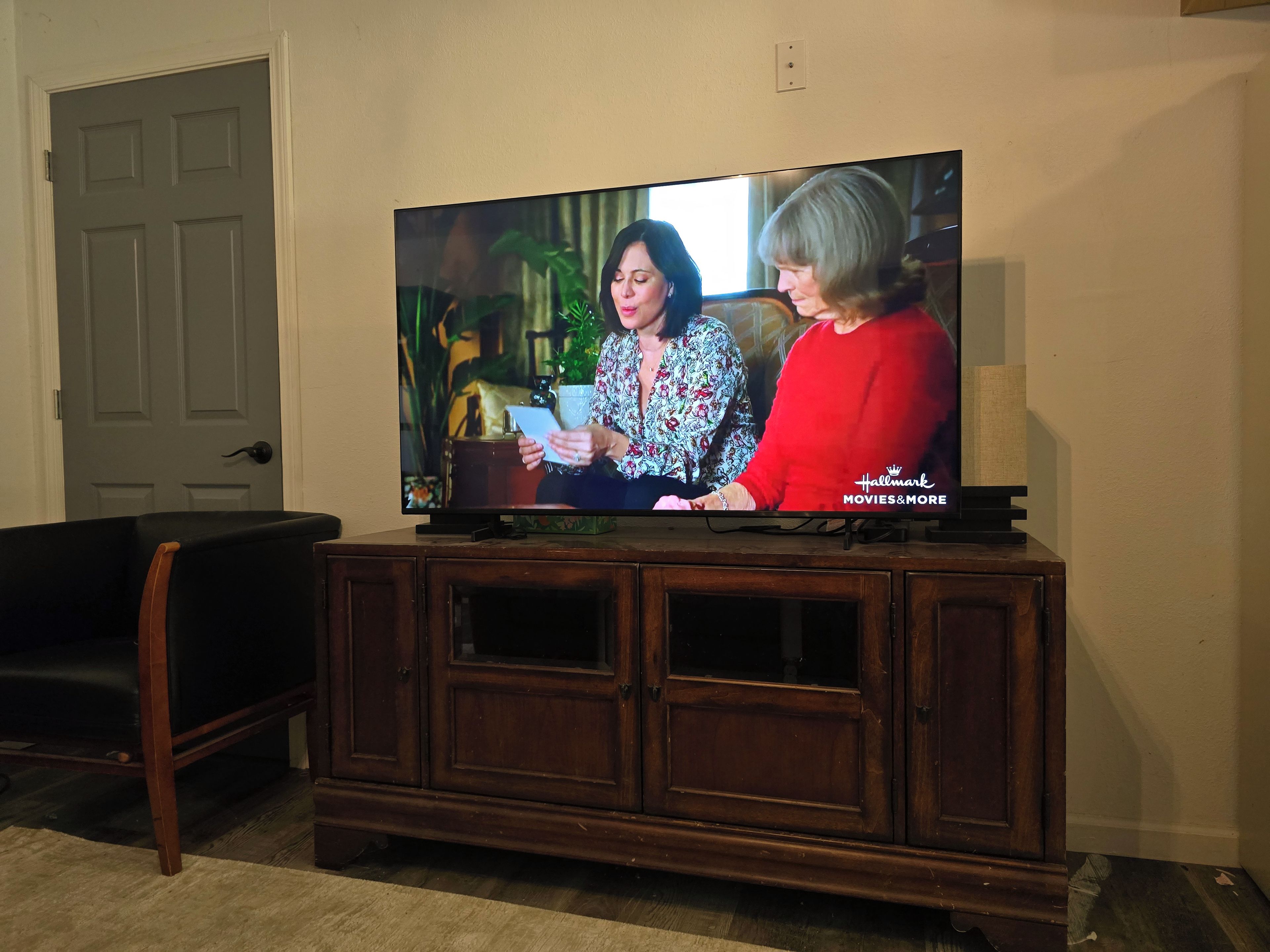 A television on a wooden cabinet with a door in the background.