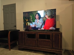 A television on a wooden cabinet with a door in the background. - Cozy 1-bedroom apartment in enchanting Sparta surounded by trees and wilderness. (Sparta)