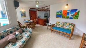 A living room with a sofa, a dining table with chairs, a kitchen area, and artwork on the walls. - New Listing (El Rodadero)