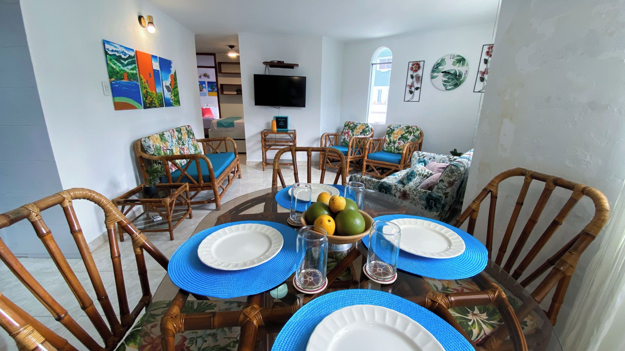 A dining area with a round table set for four, surrounded by bamboo chairs.