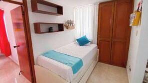 A bedroom with a bed, a wardrobe, a shelf with a ship model, and a window with curtains. - New Listing (El Rodadero)