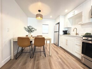 Une cuisine moderne avec des meubles blancs, un réfrigérateur en acier inoxydable et une cuisinière noire.