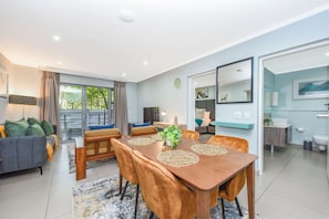A modern living room with a dining table, sofa, and a view of the outdoors. - Luxury Executive Stay  Hurlingham Sandton (Sandton)