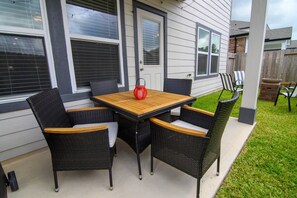 Een terras buiten met een tafel, stoelen, een rode lantaarn en een houten terrasvloer.