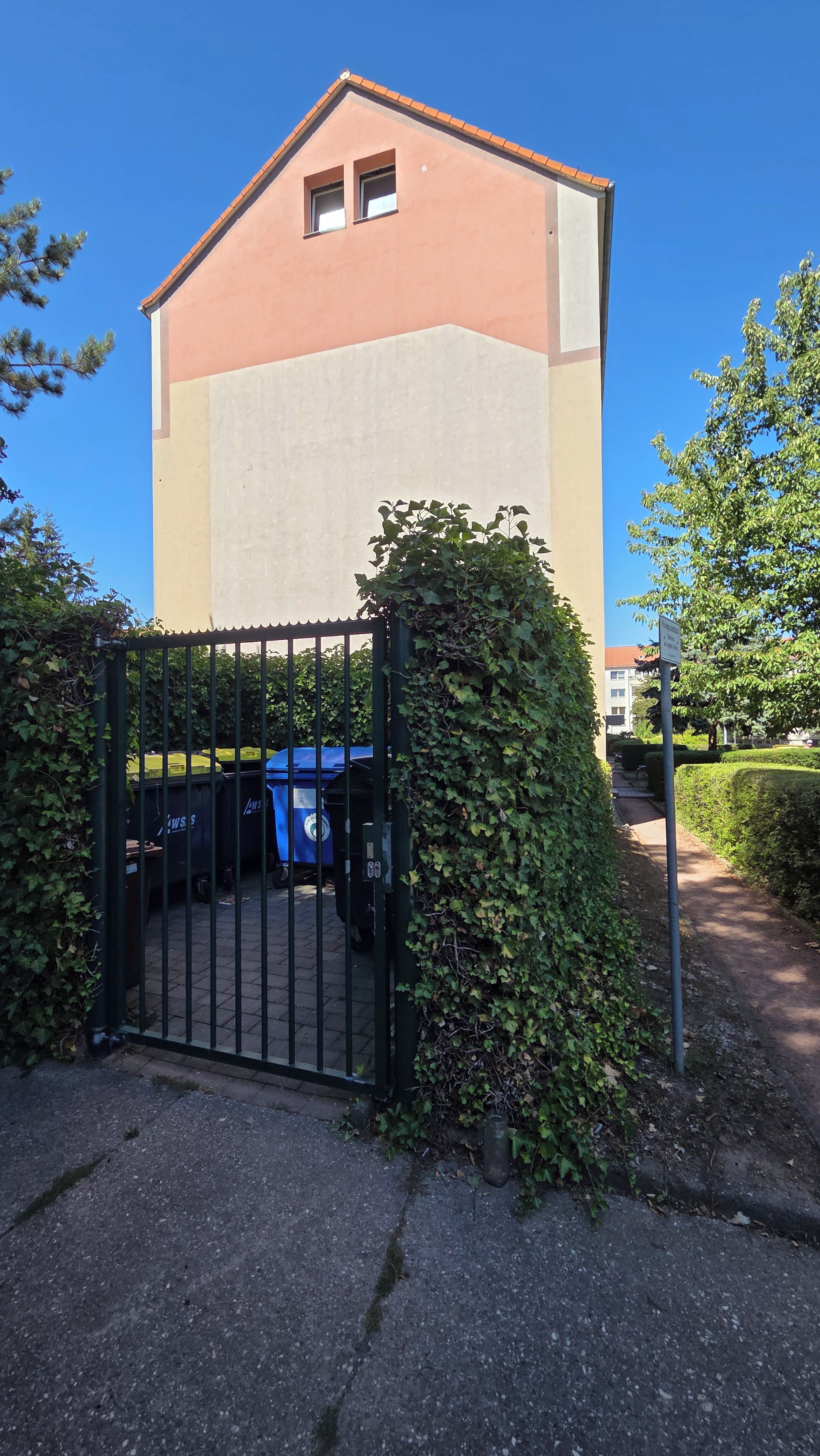 Un bâtiment doté d’une entrée fermée par un portail, sous un ciel dégagé, et un chemin menant à cet endroit.