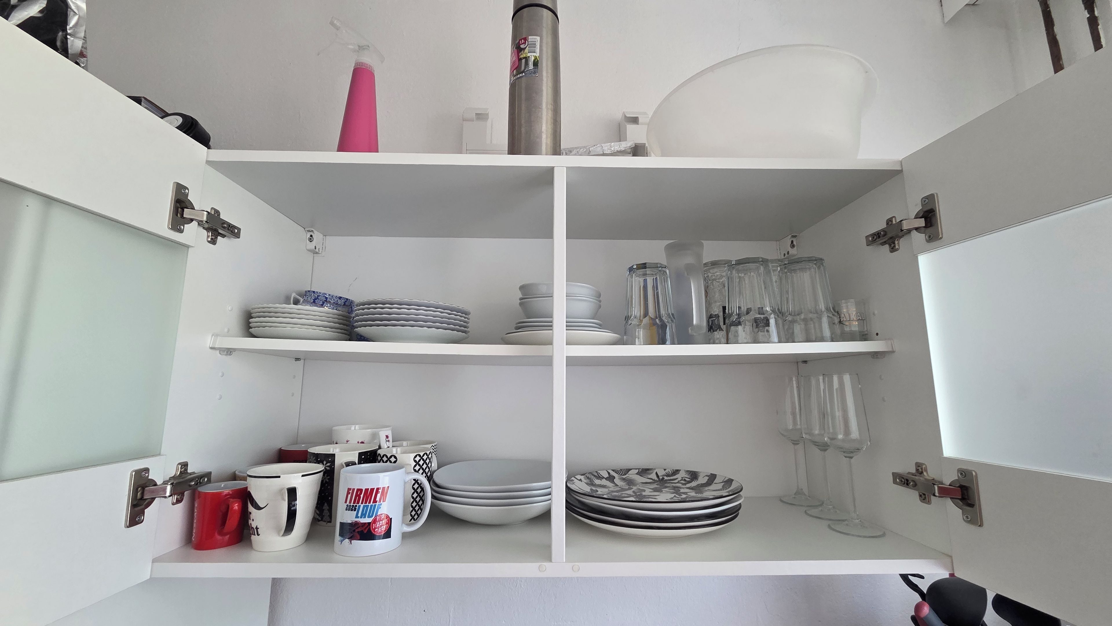 Armário de cozinha com prateleiras contendo pratos, canecas e copos.