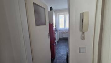 Passadís estret amb un frigorífic vermell, un telèfon i una finestra amb cortines.