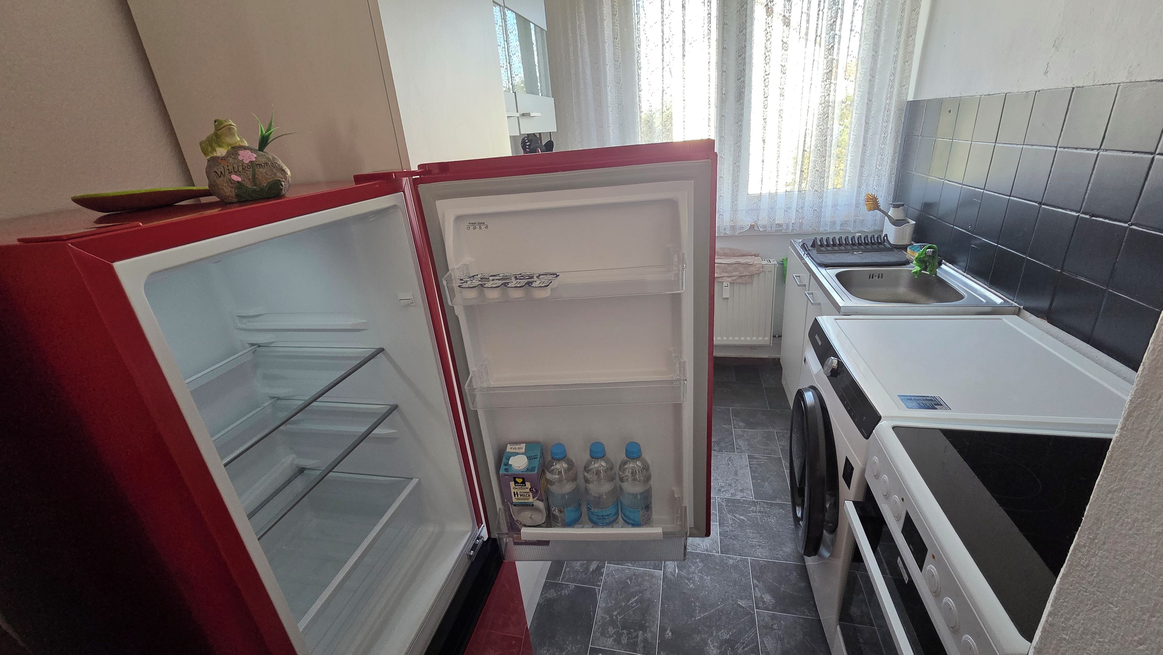 A compact kitchen with a refrigerator, a sink, and a stove.
