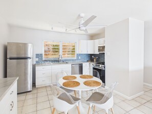 Une cuisine moderne équipée d’un réfrigérateur, d’une cuisinière et d’un coin repas avec des chaises et une table.