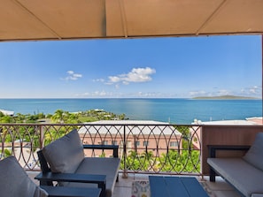 A balcony with outdoor seating, a view of the sea, and a distant island. - Sea View Bliss Remodeled 2BR Coakley Bay Condo with Buck Island Views and AC (Christiansted)