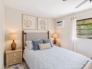 A bedroom with a bed, two bedside tables, and wall-mounted artwork. - Sea View Bliss Remodeled 2BR Coakley Bay Condo with Buck Island Views and AC (Christiansted)