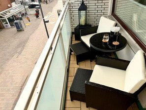 A balcony with wicker furniture, a table with glasses, and a brick wall. - Holiday Apartment With 1 Bedroom (Sylt)