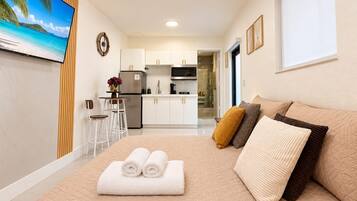 Habitació d'hotel amb llit, televisió, zona de cuina i bany.