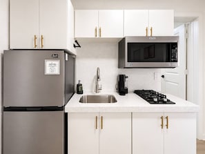 Una cocina moderna con electrodomésticos de acero inoxidable, un microondas integrado y una estufa a gas.