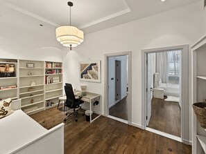 A modern home office with a glass desk, black office chair, and a large bookshelf. - Tiara Aquamarine - 705 3BD (Dubai)