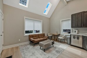A modern kitchen with a dining area, a sofa, and a coffee table. - Walk to Metro - 1.2 Miles to NIH & Walter Reed (Bethesda)