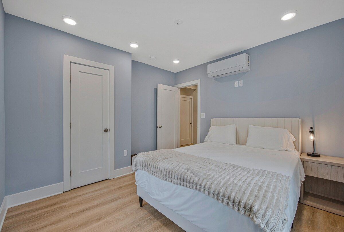Ein Schlafzimmer mit einem Bett, einem Nachttisch, einer Klimaanlage und einer Tür.