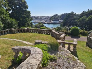 Jardí de pedra amb vista a un port i edificis a la distància.