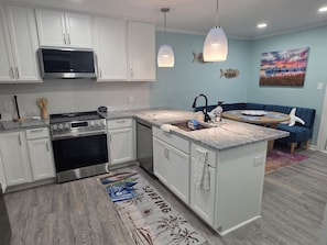 A modern kitchen with white cabinetry, a stainless steel stove, and a granite countertop. - 2-bedroom condo in enchanting Morehead City minutes away from Atlantic Beach (Morehead City)