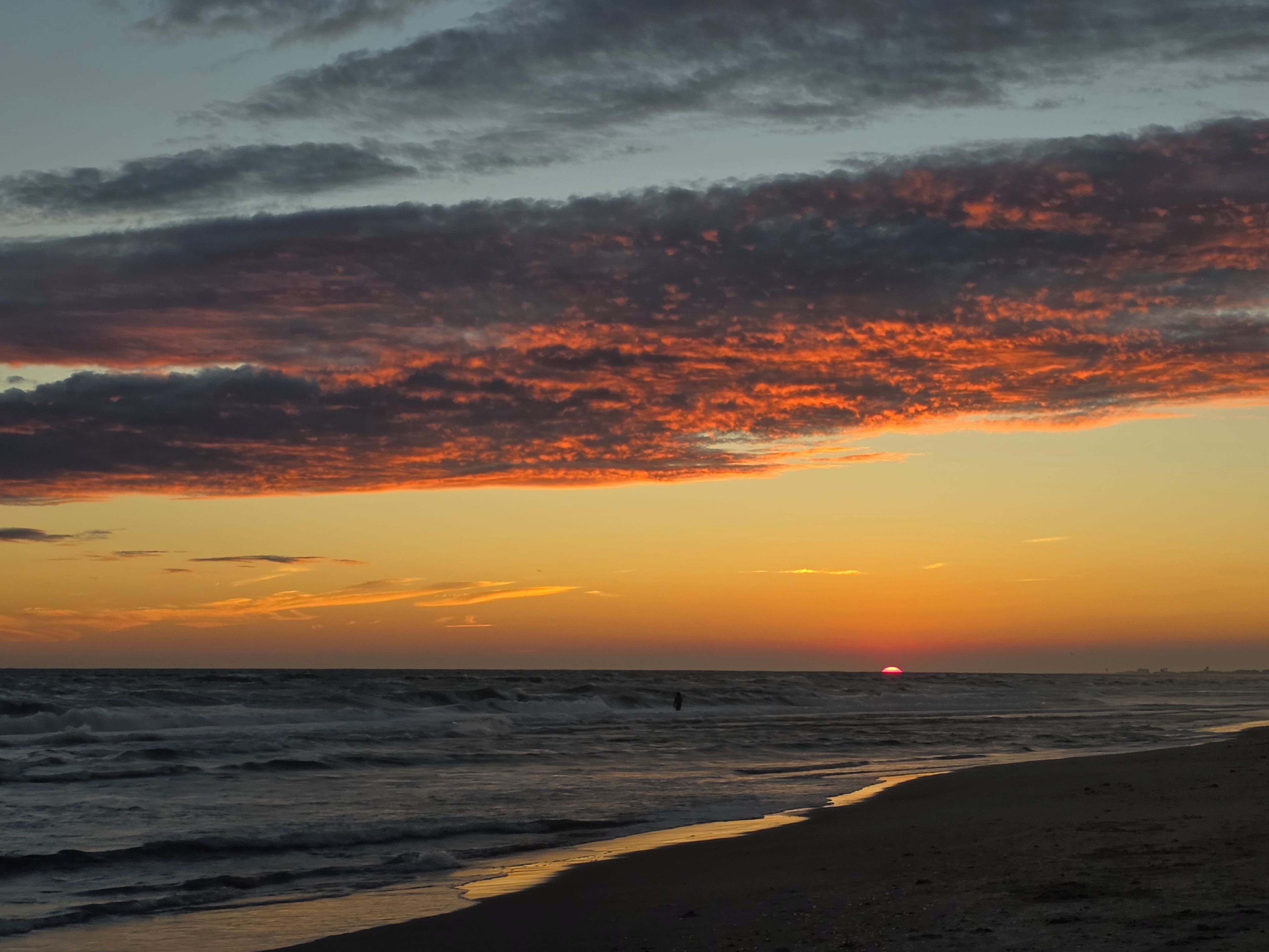 Une plage avec des vagues et un coucher de soleil.