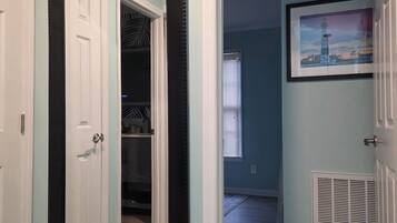 A hallway with a large mirror, a door, a closet, and a vent.