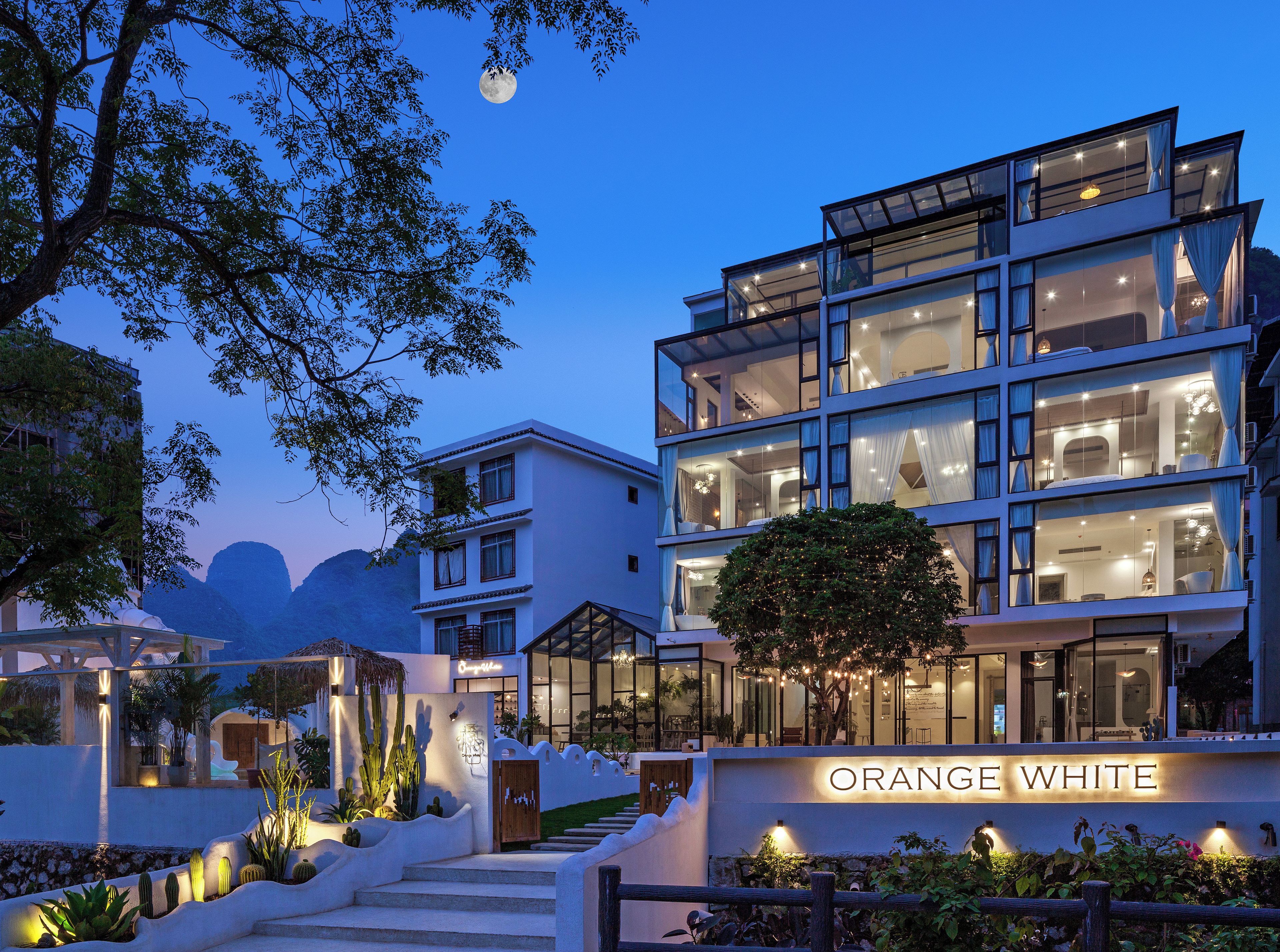 Un hotel de varios pisos con un diseño moderno, con ventanas amplias y una entrada bien iluminada.