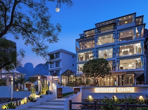 Un hotel de varios pisos con un diseño moderno, con ventanas amplias y una entrada bien iluminada.