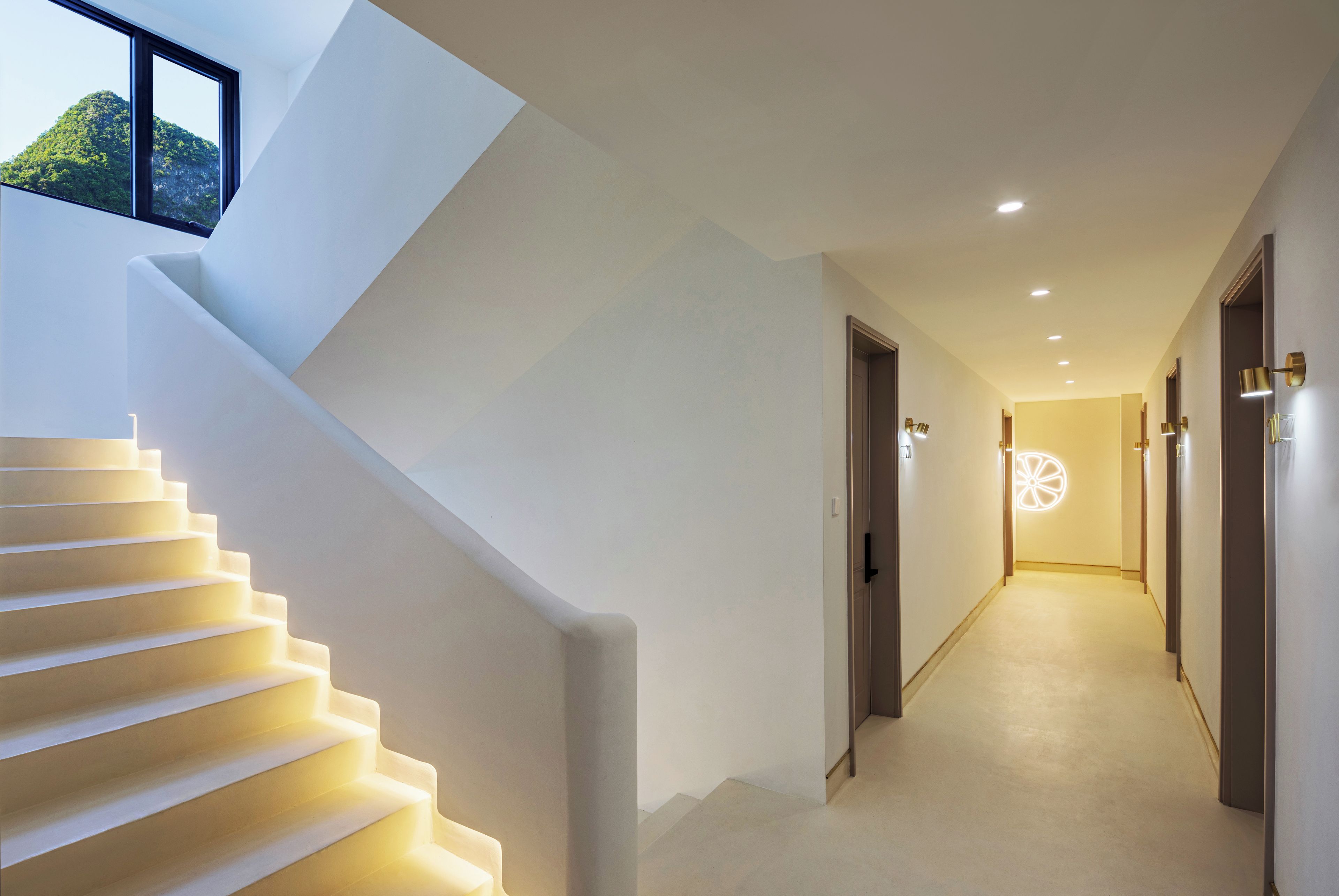 Un interior moderno con una escalera que lleva a una distribución, un pasillo con puertas y un tragaluz.