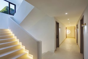 Un interior moderno con una escalera que lleva a una distribución, un pasillo con puertas y un tragaluz.