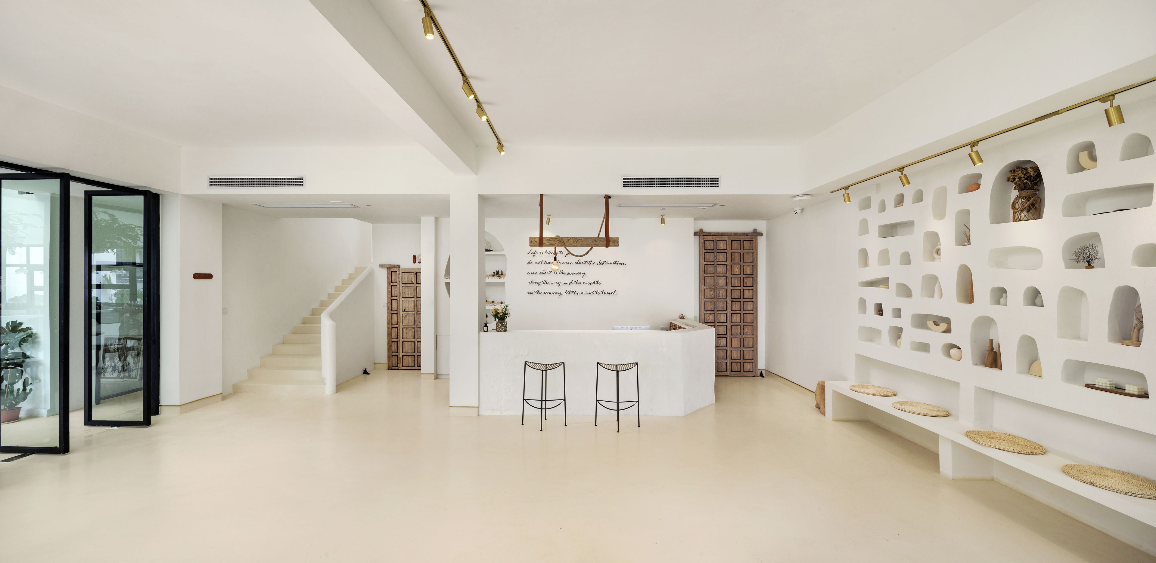 Een modern interieur met een centraal receptiegedeelte, een trap en een wand met planken.