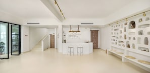 Ein modernes Interieur mit einer zentralen Rezeption, einer Treppe und einer Wand mit Regalen.
