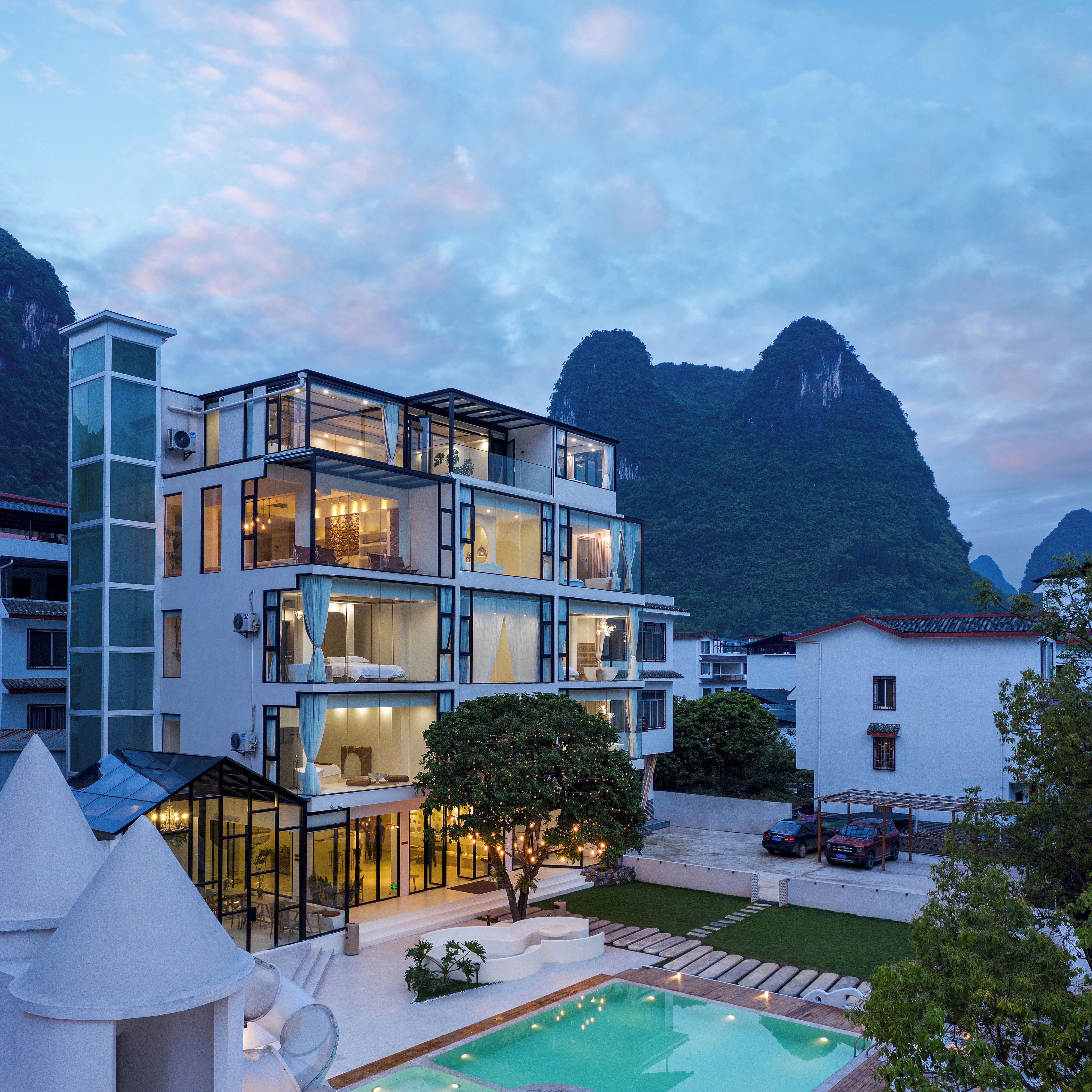 Ein mehrstöckiges Hotel mit Pool, umgeben von Bergen.