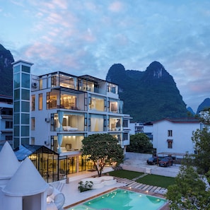 Ein mehrstöckiges Hotel mit Pool, umgeben von Bergen.
