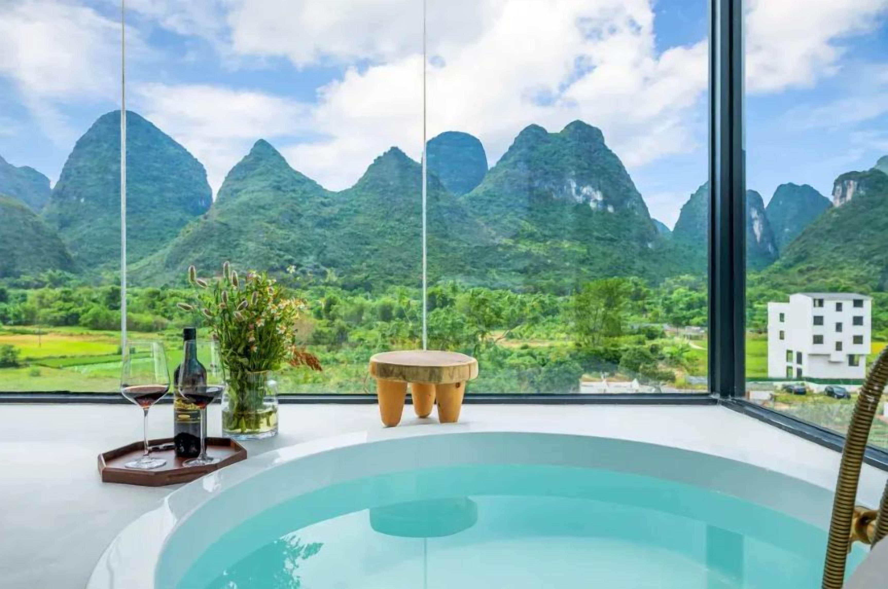 Un jacuzzi con vista a la montaña, una botella de vino y un florero con flores.