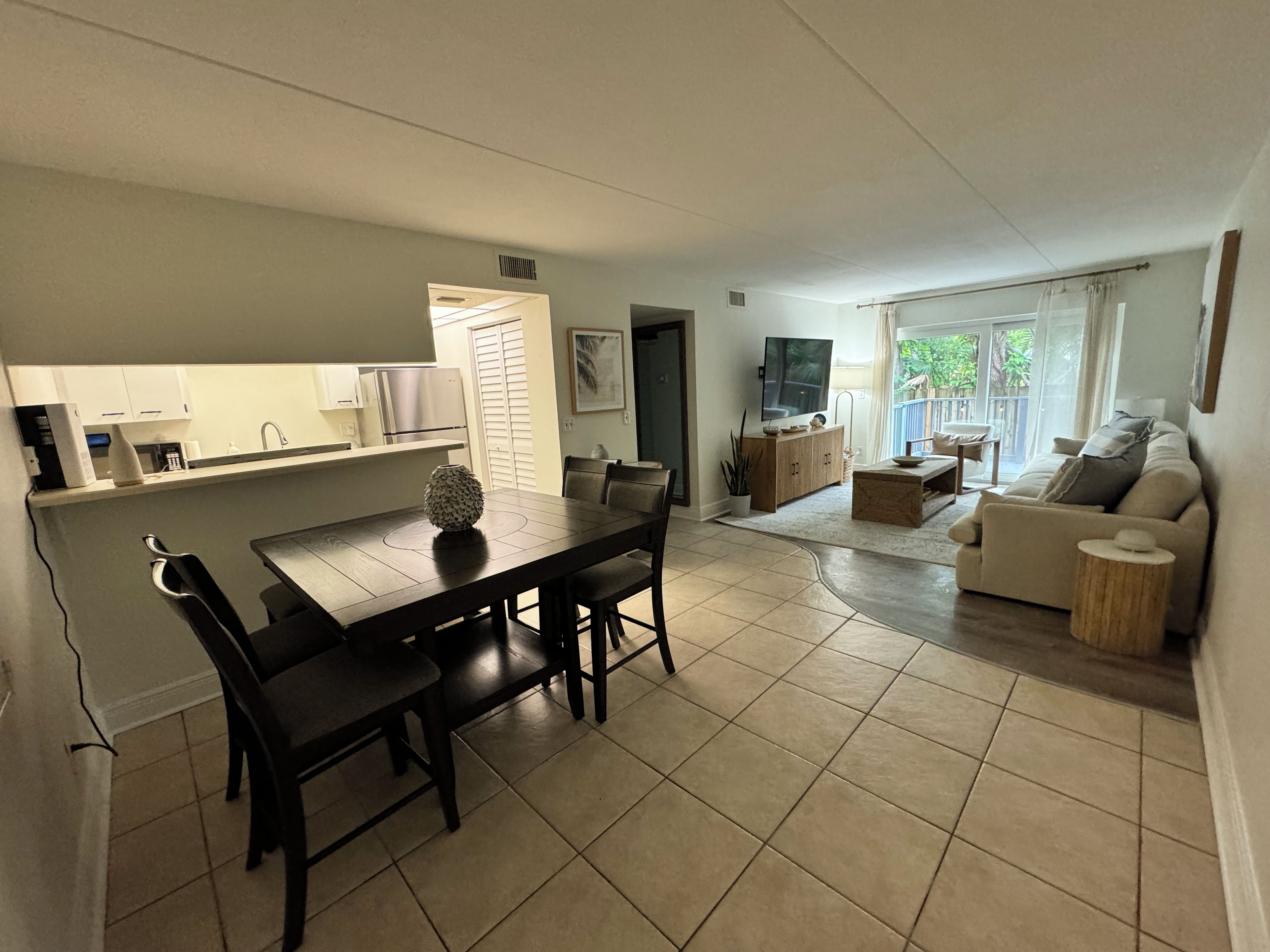 A modern living space with a dining area, kitchen, and a seating area with a sofa and coffee table.