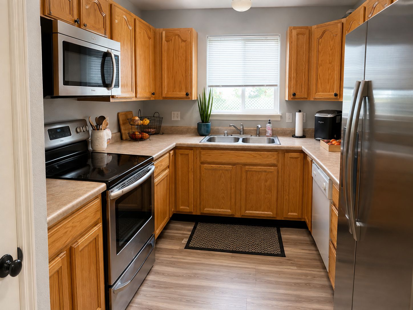 A modern kitchen with wooden cabinets, stainless steel appliances, a microwave, and a sink.