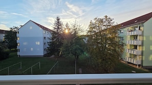 Un immeuble résidentiel doté de nombreux balcons, d’une cour verdoyante et d’arbres.