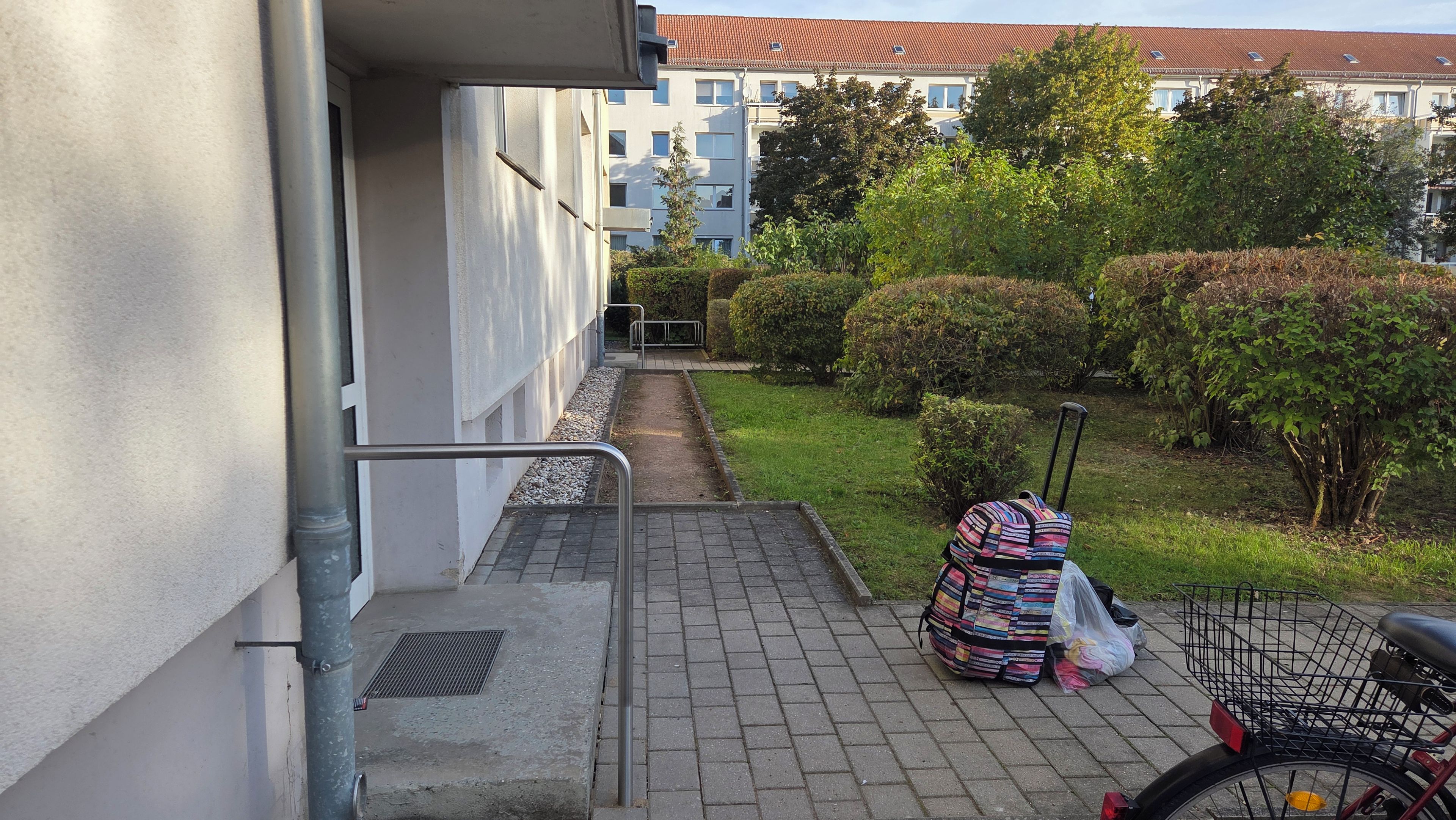 Ein Wohngebäude mit einem gepflasterten Weg, der zu einer Treppe führt.