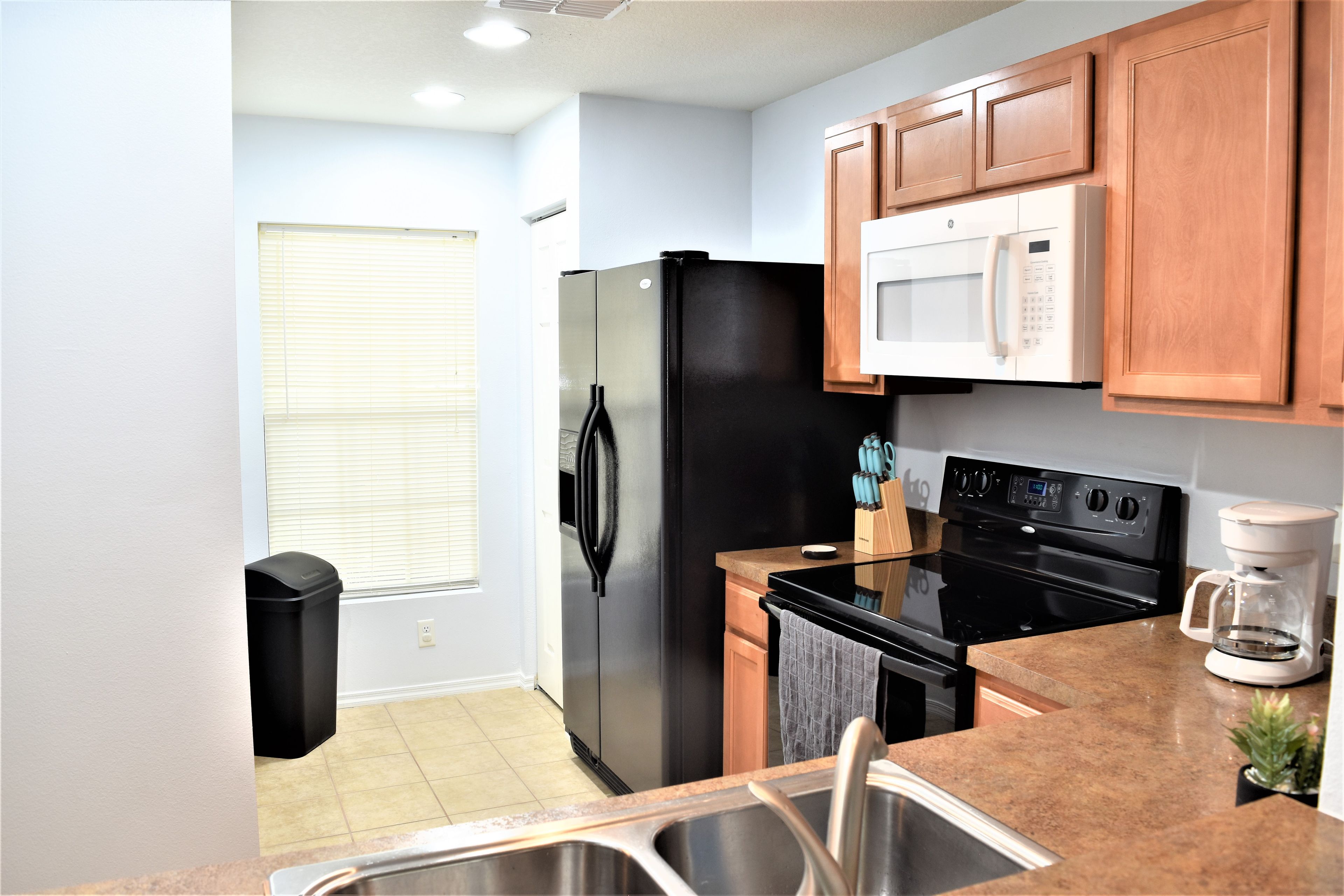 A compact kitchen with a refrigerator, microwave, stove, and sink.