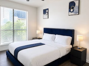 Una habitación de hotel con una cama grande, dos mesitas de noche y una ventana con persianas.