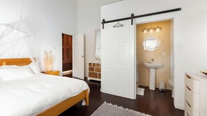 A bedroom with a bed, bedside table, and a hanging mosquito net. - Dragonfly Villa - By Zenbreak (Holetown)