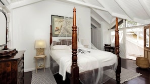 Un lit à baldaquin, une table de chevet avec une lampe et un tableau encadré accroché au mur.